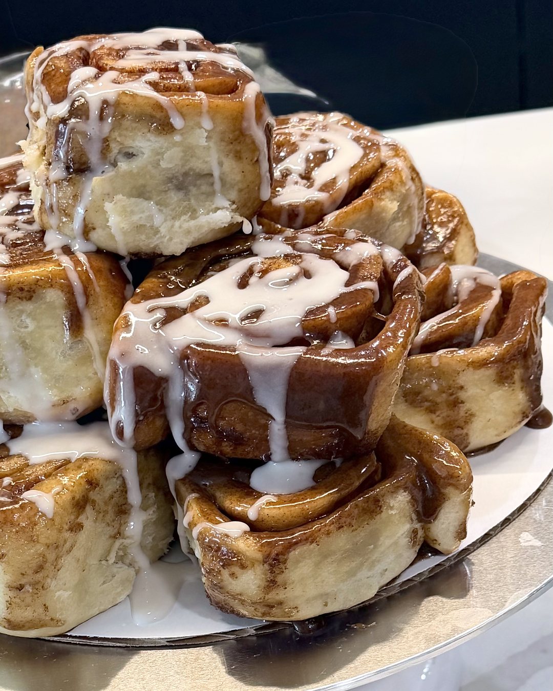 Iced cinnamon rolls on a cake stand