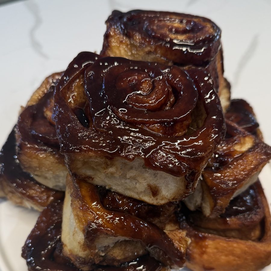 Glazed cinnamon rolls stacked on a plate