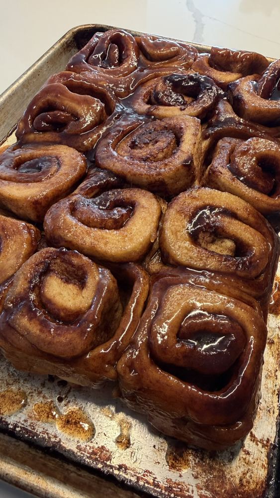 Nine glazed cinnamon rolls in the pan, fresh out of the oven