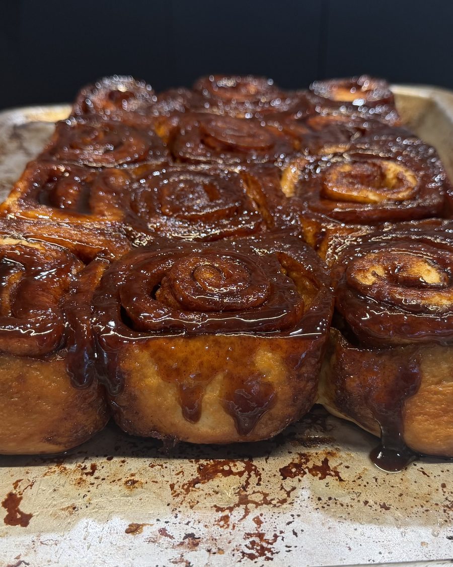 A tray of glazed cinnamon rolls, seen from the side